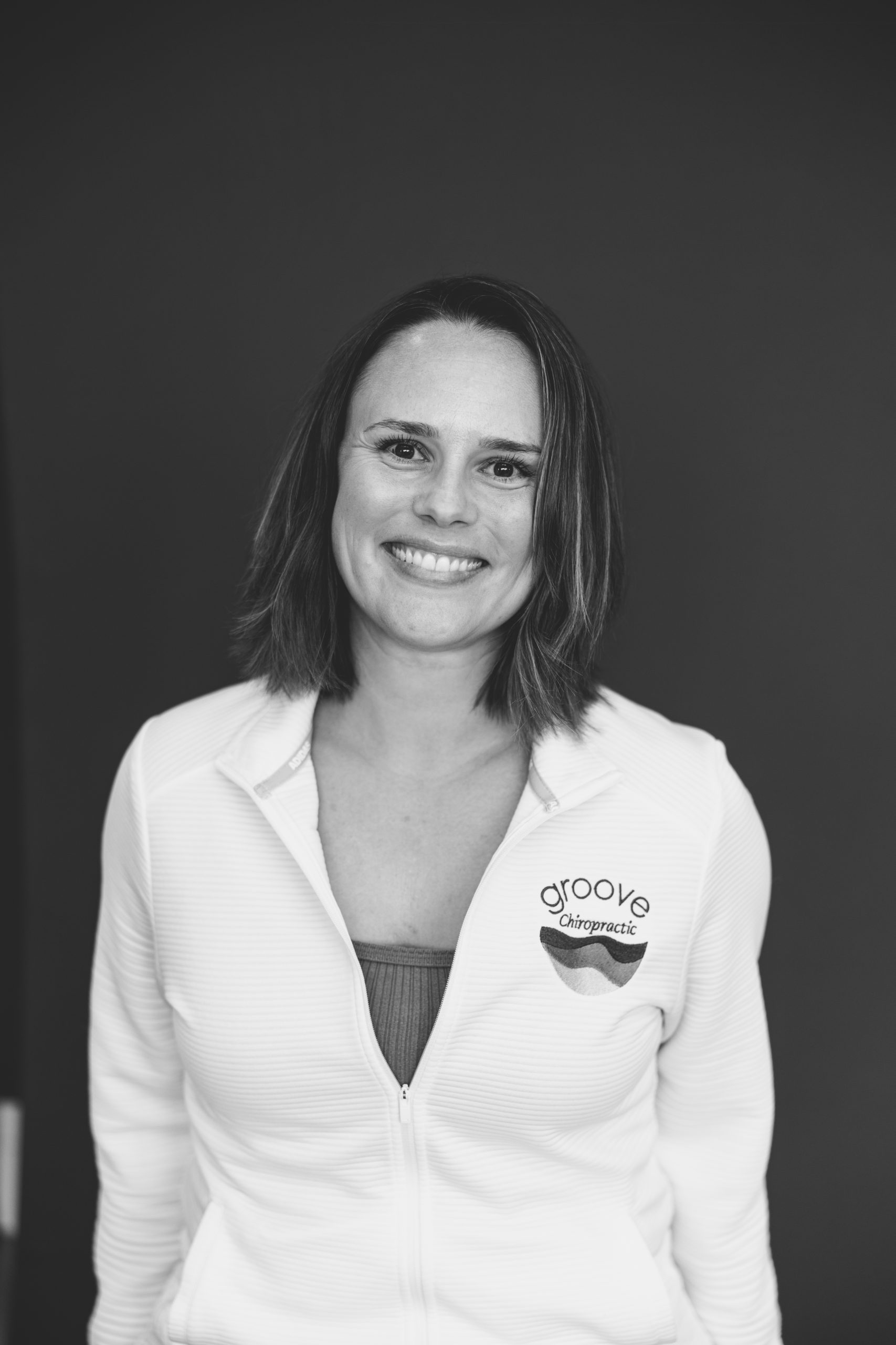 Cydney Keller Brinson, DC A black and white photo of Dr. Cydney, who smiles wearing a Groove Chiropractic shirt.