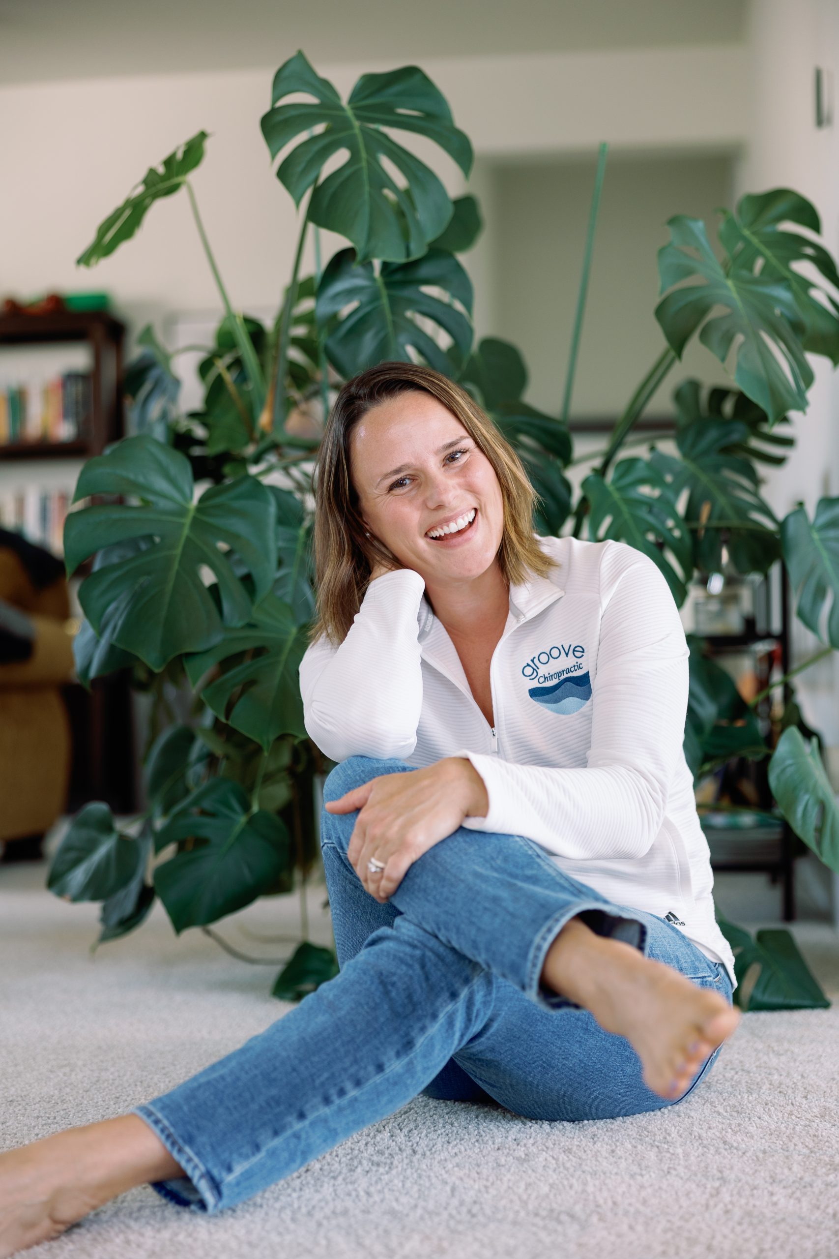 Dr. Cydney sitting on the floor and smiling wearing a Groove Chiropractic shirt.